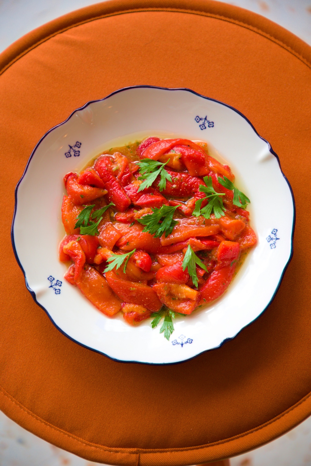 Poivrons marinés et persil dans une assiette bordée de bleu